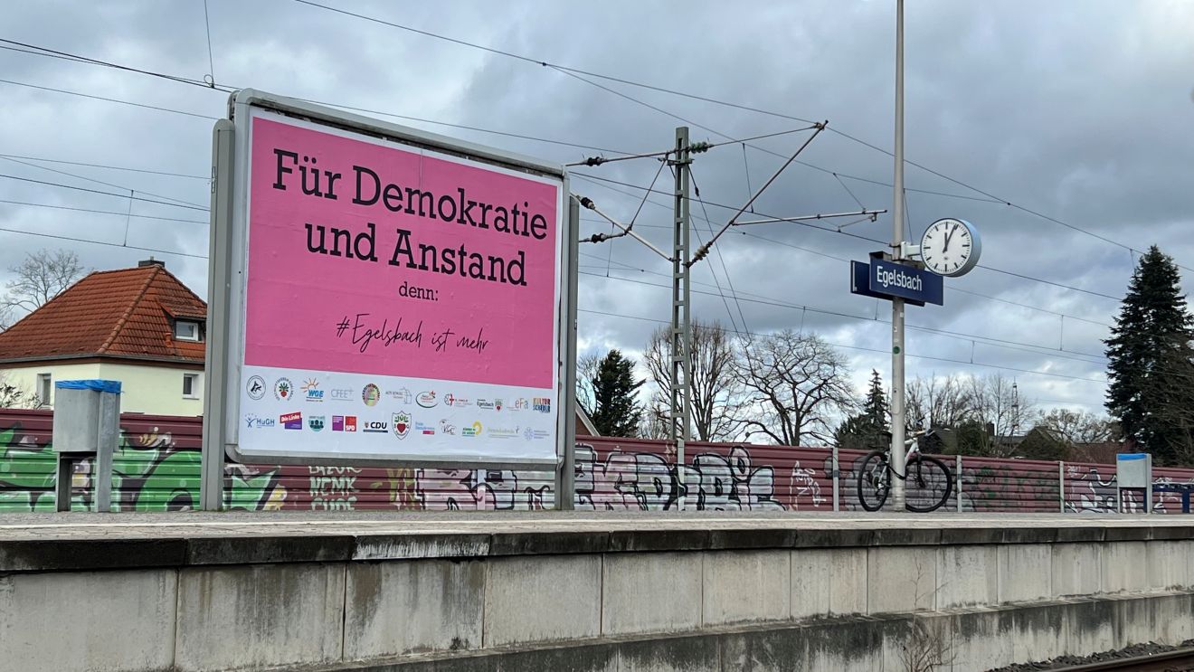 Große Plakatwand mit der Aufschrift "Für Demikratie und Anstand - denn #Egelsbach ist mehr" am Egelsbacher Bahnhof